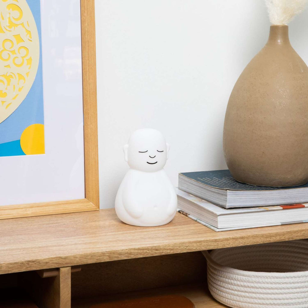 The breathing buddha in the entry of a house, next to a painting and vase, which is on top of two books.
