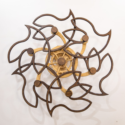 Floral-inspired wall art of overlapping dark wooden petals swirling around a light central mechanism, evoking gentle, rhythmic motion.