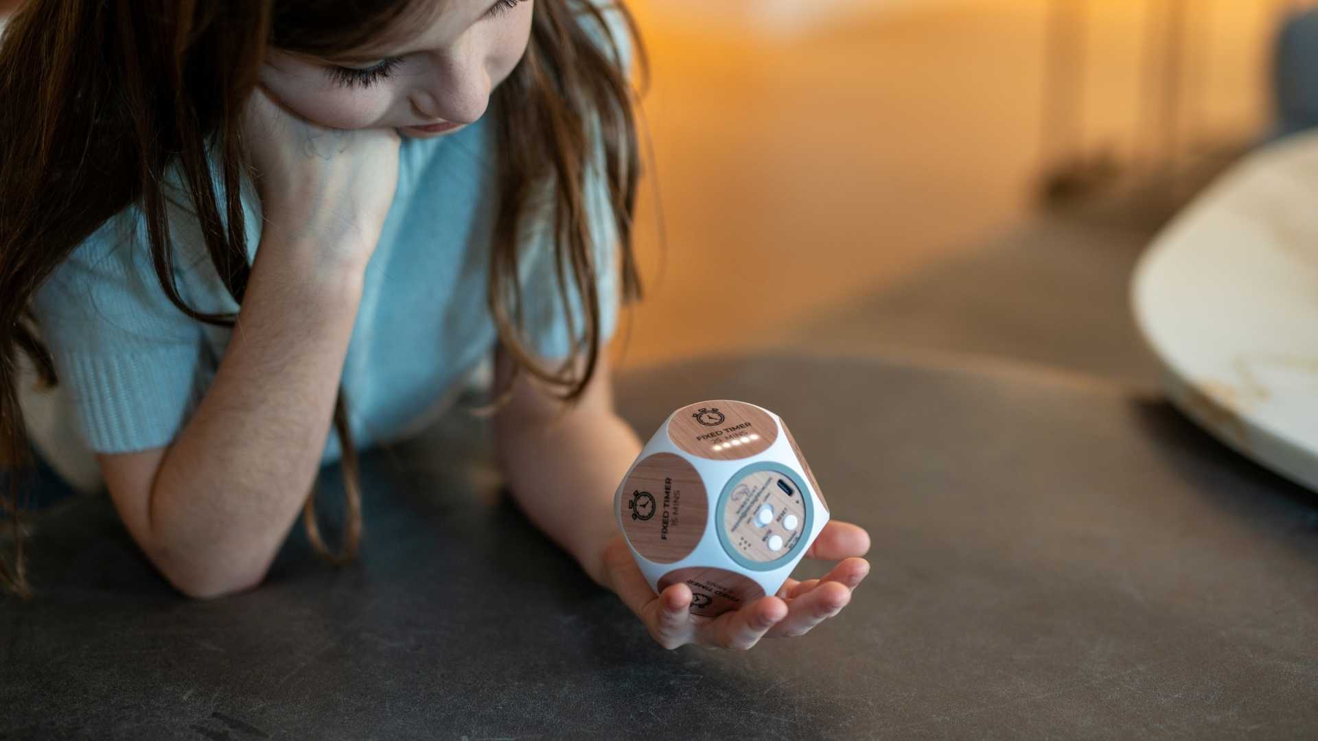 Child holding a mindfulness habit cube on a table