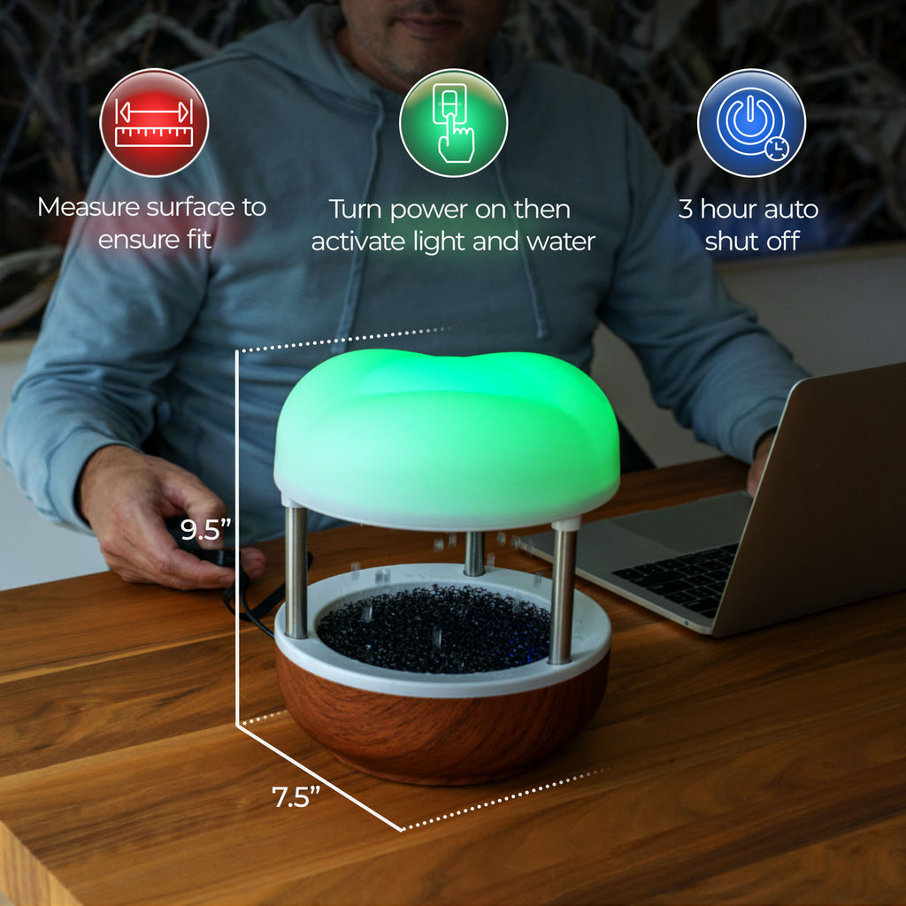 Calming Cloud Fountain glowing green, dimensions 9.5" tall and 7.5" wide, with 3-hour auto-shutoff, on a table beside a laptop.