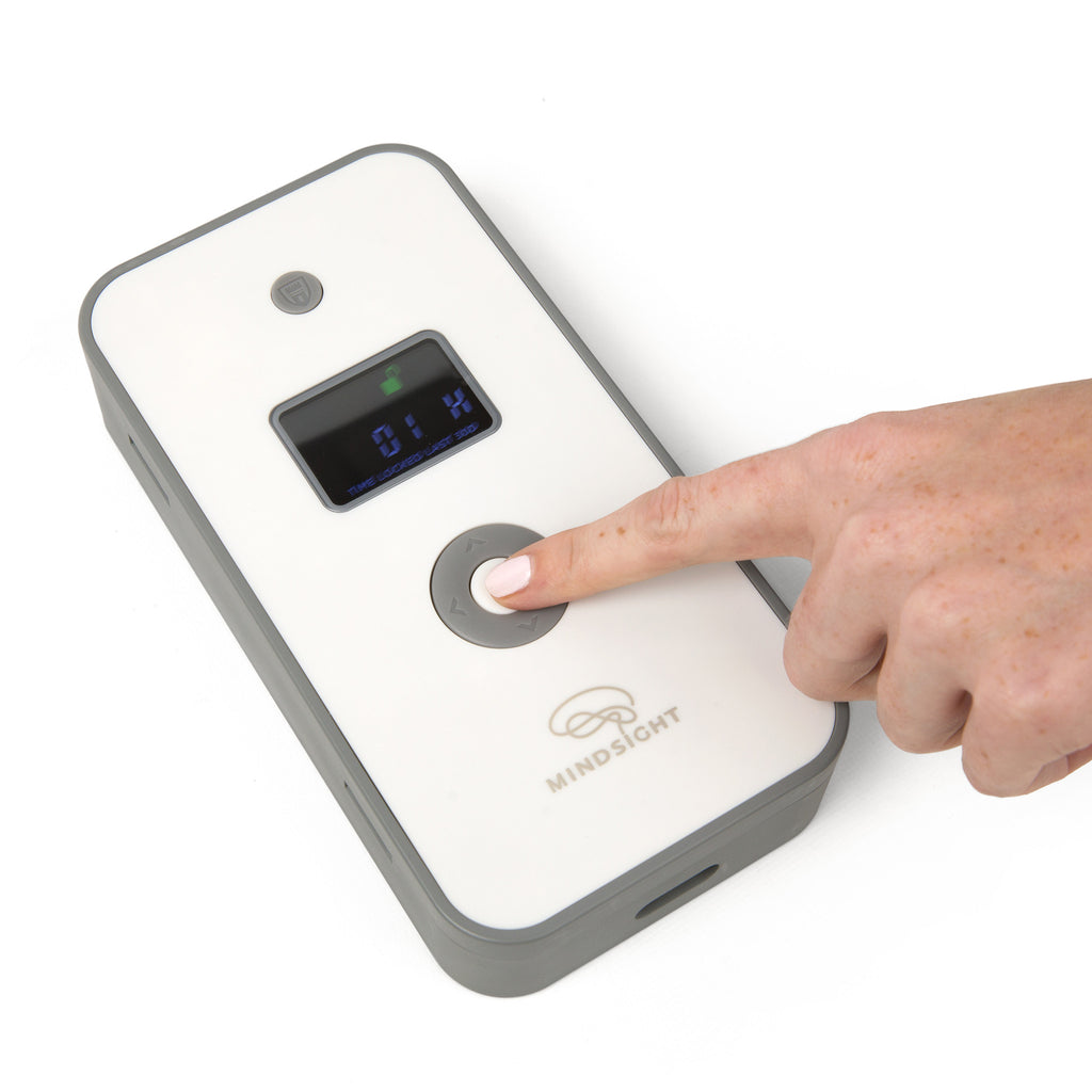 Finger pressing the central button on the Mindsight Personal Timed Lock Box with a digital display showing 01H.