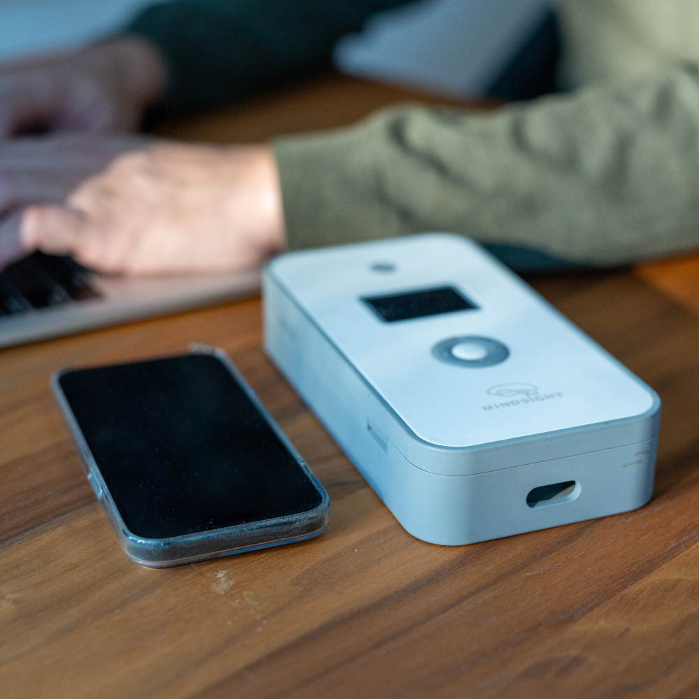 A black Mindsight timed lockbox on a white countertop with a blurred kitchen background.