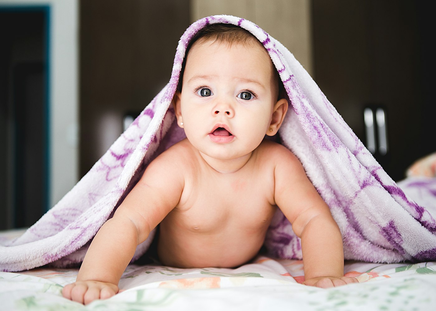 A baby wrapped in a blanket on a bed