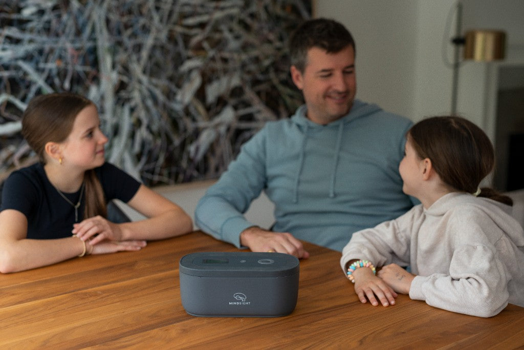 A parent and two kids at a table with a closed Mindsight lock box
